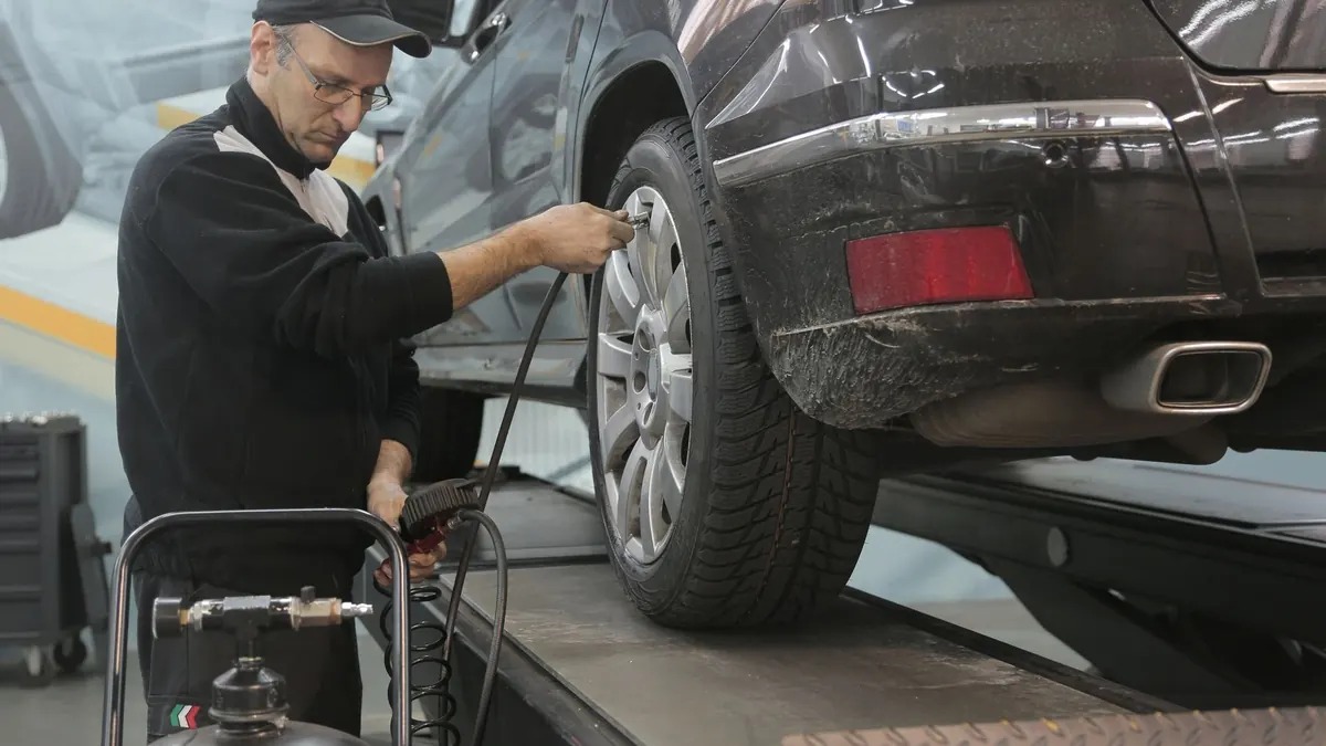 Automehaničar provjerava tlak u gumi automobila podignutog na dizalici